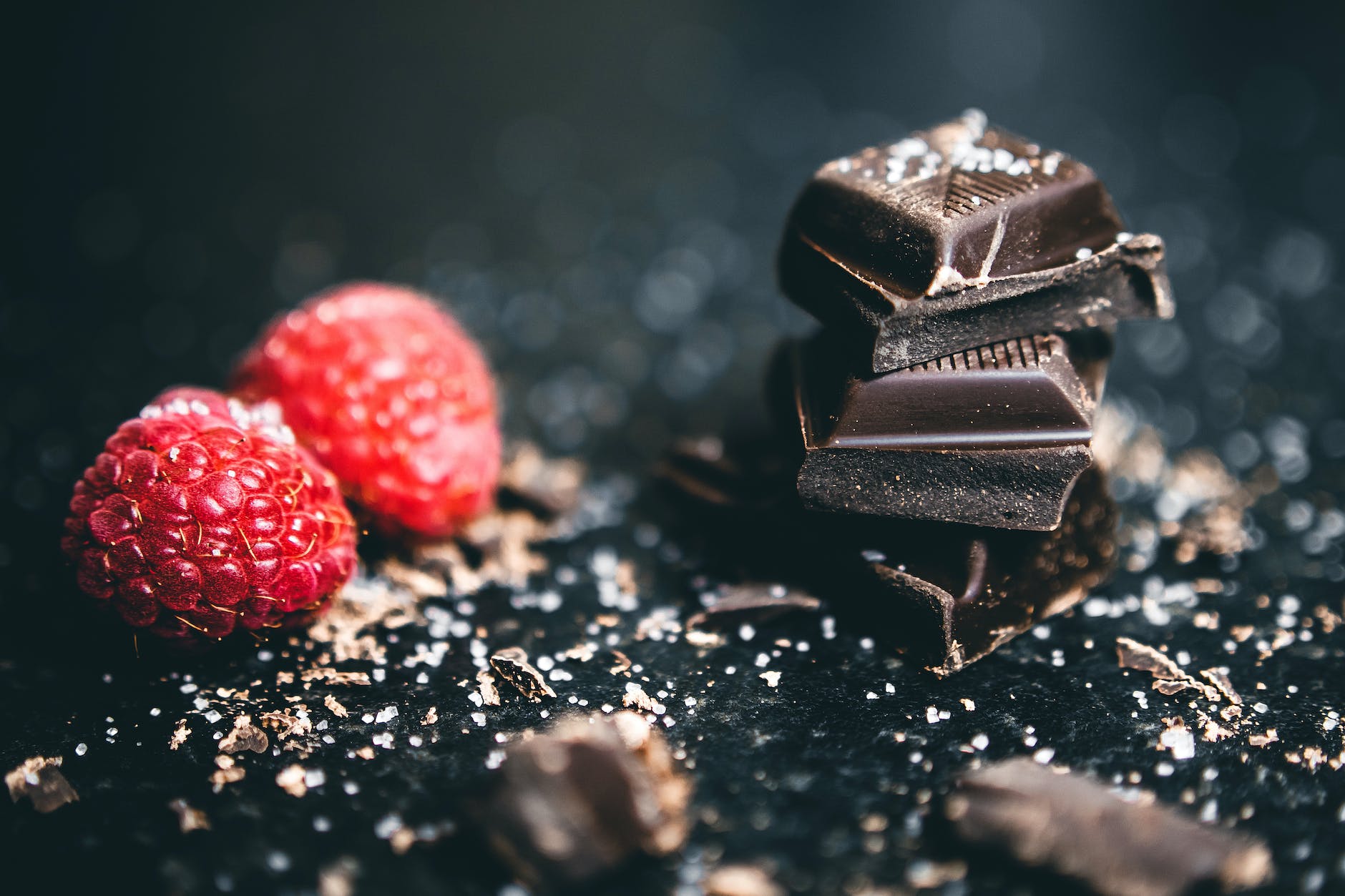 close up photo of stacked chocolates bars beside raspberries