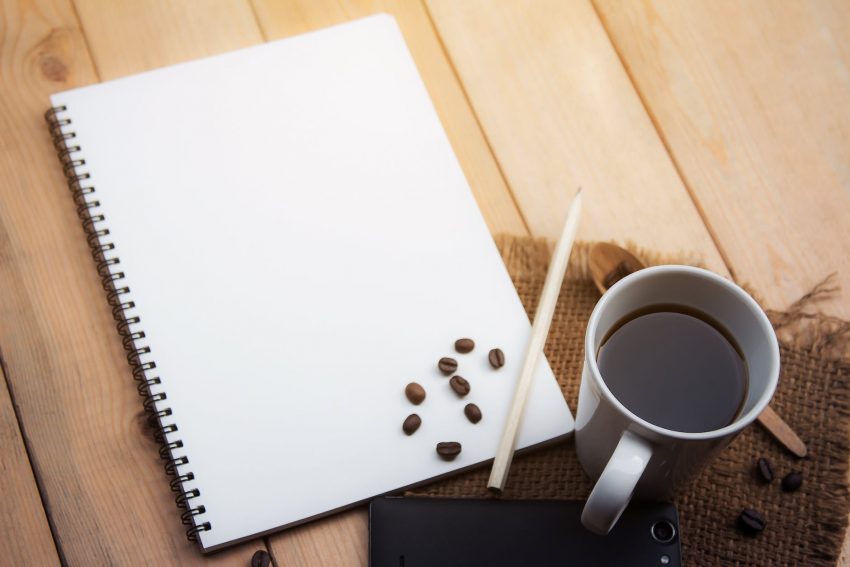 white sketch pad beside cup of coffee